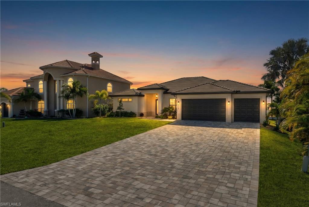 Image 4: View of front of house featuring a yard, decorative driveway, stucco siding, and an attached garage