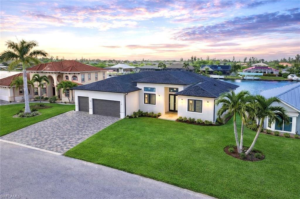 Image 1: View of front of home with a lawn, decorative driveway, stucco siding, an attached garage, and roof with shingles (Rendered photo)