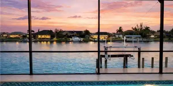 Image 4: Outdoor pool with boat lift, a dock, a lanai, and a sunroom (Rendered photo)
