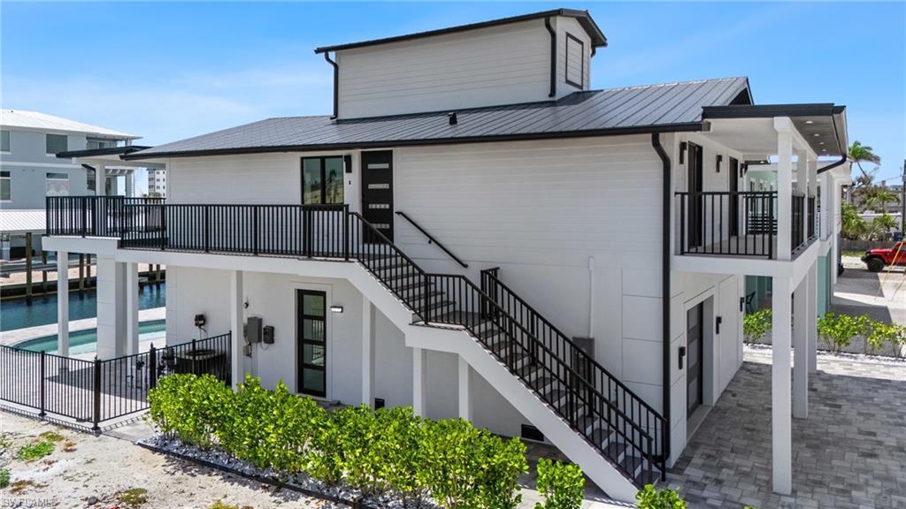 Image 4: Back of house with stairs, metal roof, a patio area, and fence- Virtually Edited