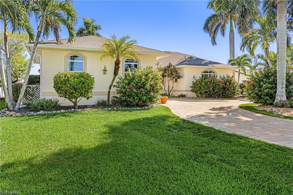 Image 4: View of front facade with stucco siding, a front yard, decorative driveway, and a shingled roof