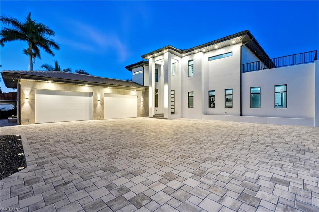 Image 1: Modern home featuring decorative driveway, an attached garage, and stucco siding