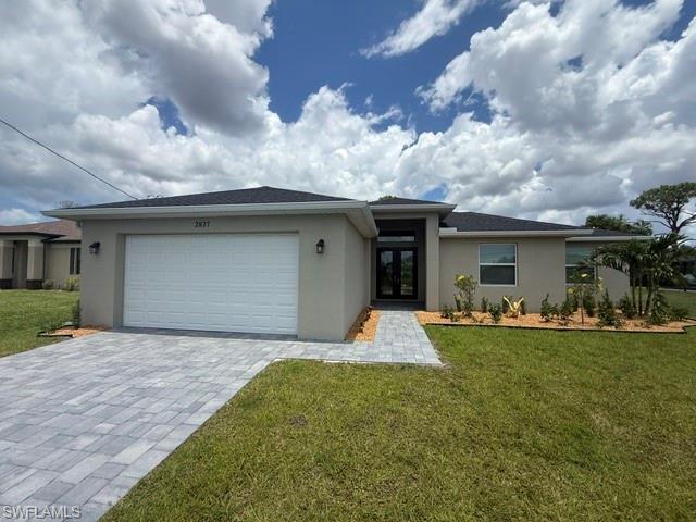 Image 3: Contemporary stucco exterior featuring a two-car garage, paver driveway, and a covered entry with double front doors