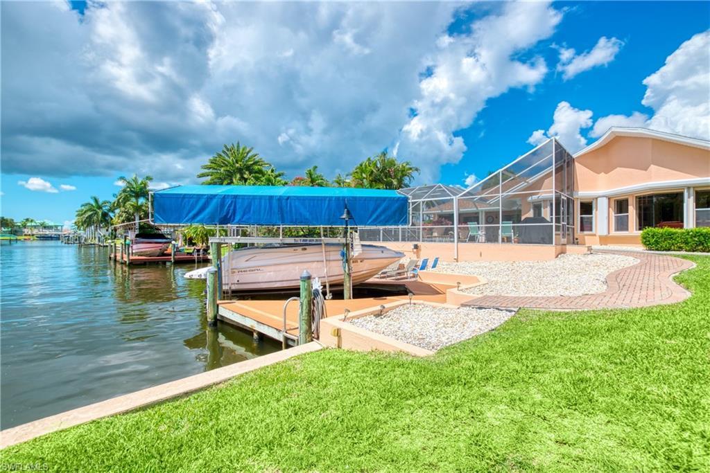 Image 4: Dock with boat lift, a sunroom, glass enclosure, and a yard