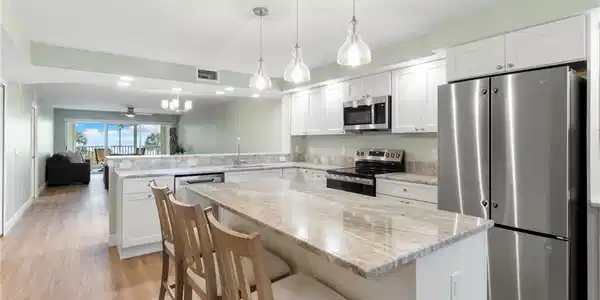 Image 2: Kitchen featuring stainless steel appliances, open floor plan, a breakfast bar area, white cabinetry, and light wood-style floors