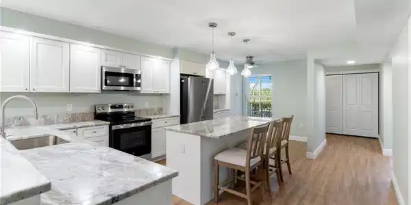 Image 3: Kitchen with appliances with stainless steel finishes, pendant lighting, a kitchen bar, light stone countertops, and a center island