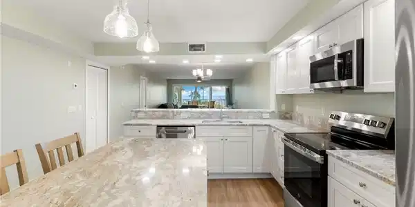 Image 4: Kitchen featuring stainless steel appliances, decorative light fixtures, white cabinetry, a chandelier, and light wood-style floors