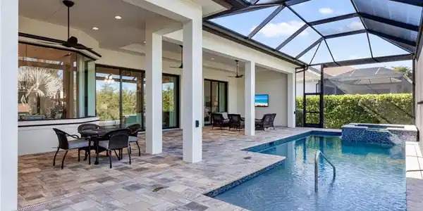 Image 3: View of pool with outdoor dining space, a sunroom, a patio, a pool with connected hot tub, and a lanai