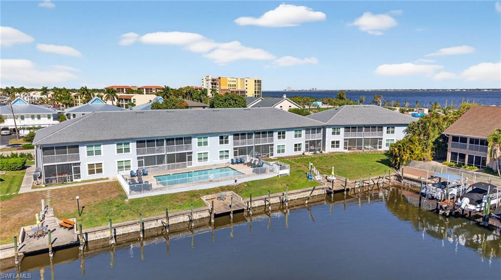 Image 3: Back of property featuring a community pool, a water view, a patio area, and a lawn