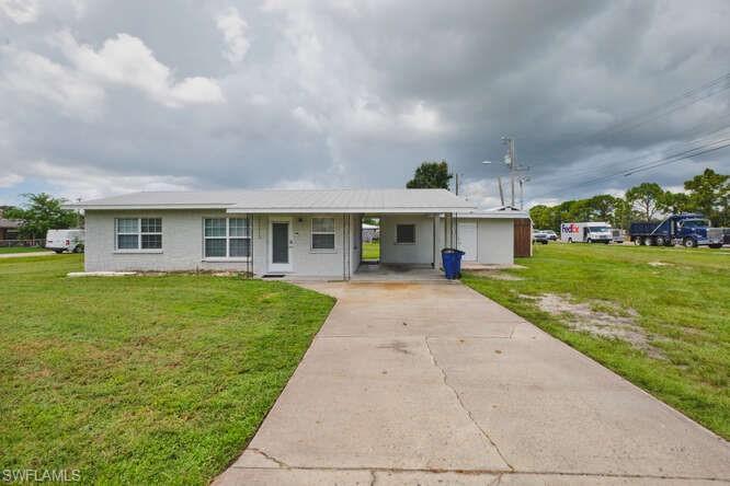 Image 2: View of front facade featuring a front lawn, a carport, concrete driveway, and a porch