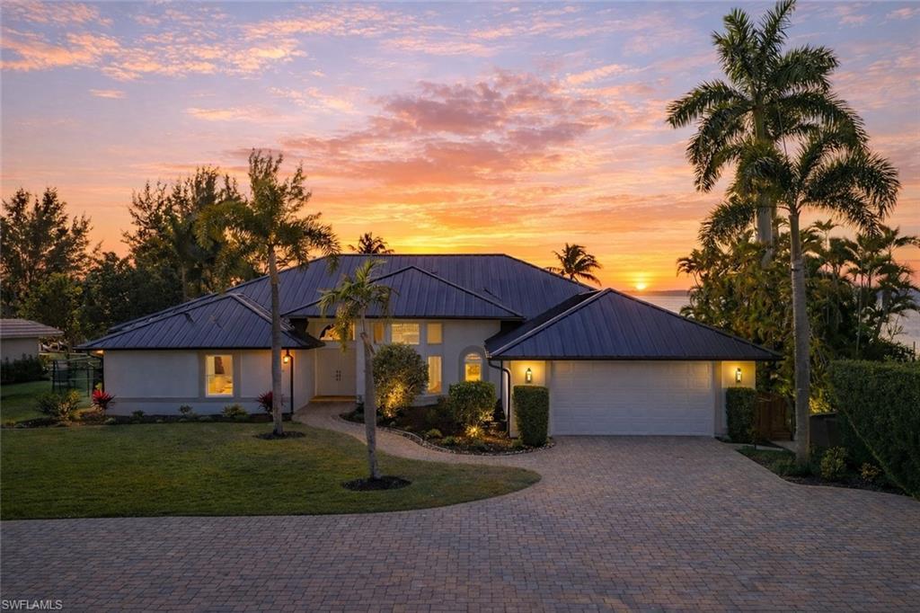 Image 4: View of front facade featuring driveway, a front yard, a standing seam roof, and a garage
