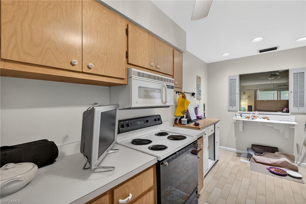 Image 4: Kitchen with electric range, light countertops, microwave, recessed lighting, and ceiling fan