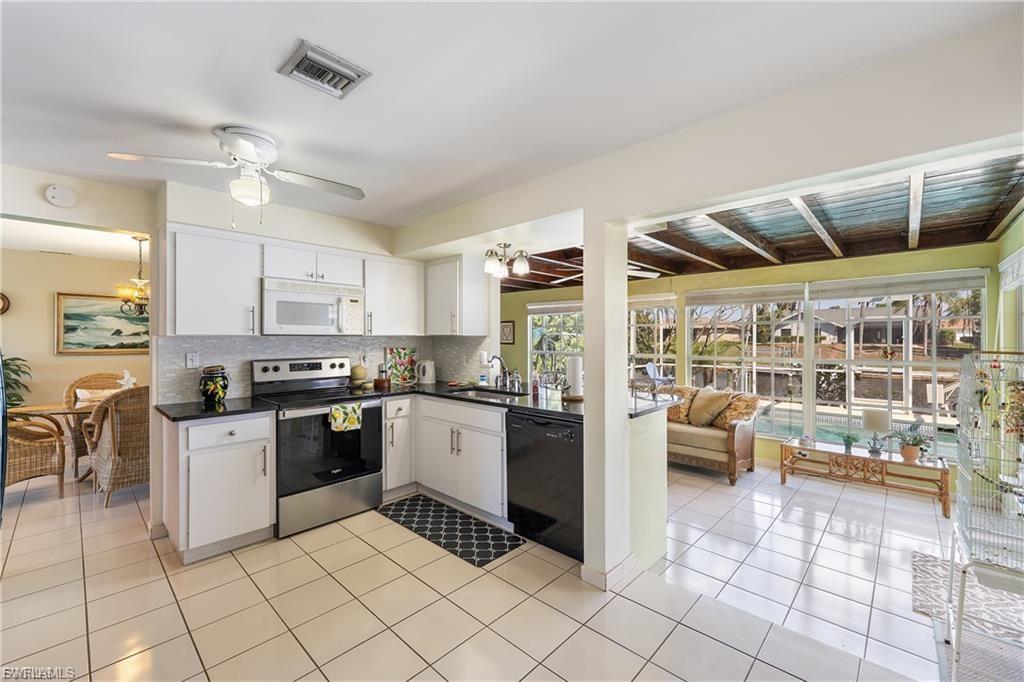Image 3: Kitchen featuring stainless steel range with electric cooktop, white microwave, tasteful backsplash, white cabinetry, and black dishwasher