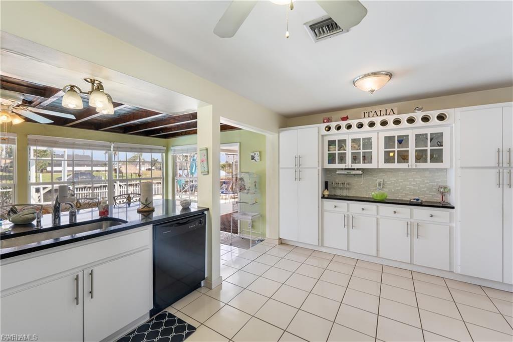 Image 4: Kitchen with ceiling fan, white cabinets, dishwasher, glass insert cabinets, and tasteful backsplash