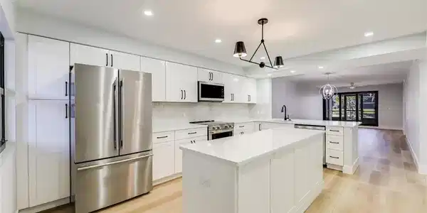 Image 2: Kitchen with stainless steel appliances, suspended lighting, light wood-type flooring, a peninsula, and white cabinetry