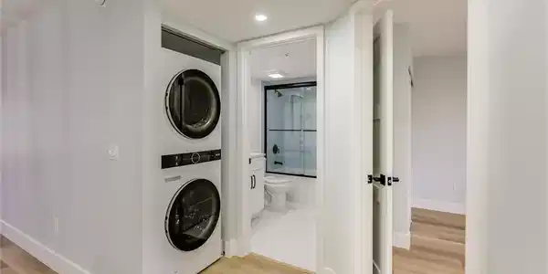 Image 4: Laundry area with stacked washer / dryer, light wood-style floors, and recessed lighting