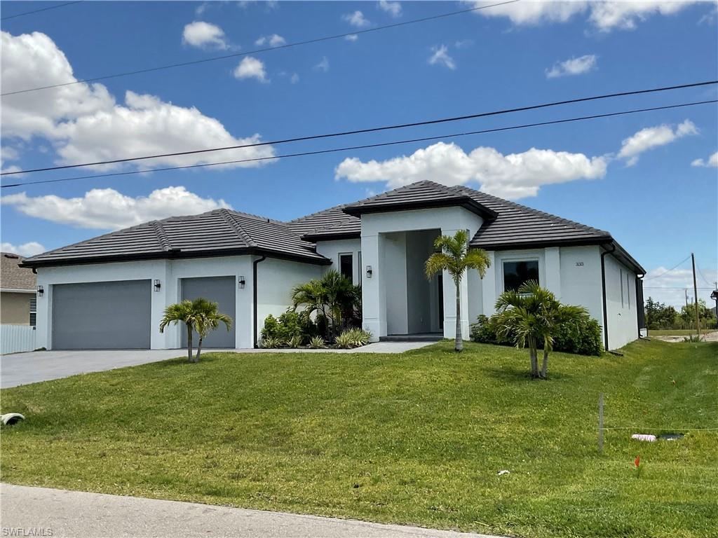 Image 2: The property features a white exterior, a dark tiled roof, and a well-maintained green lawn