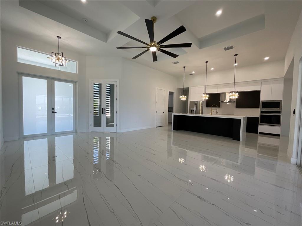 Image 3: The property features an open-concept living space with polished tile flooring, a contemporary kitchen with a large island, and recessed lighting