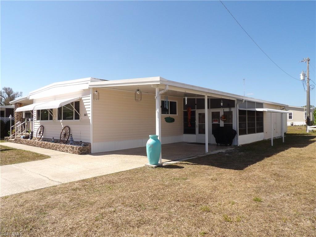 Image 2: View of front of property with an attached carport, a front lawn, and driveway
