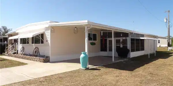 Image 2: View of front of property with an attached carport, a front lawn, and driveway
