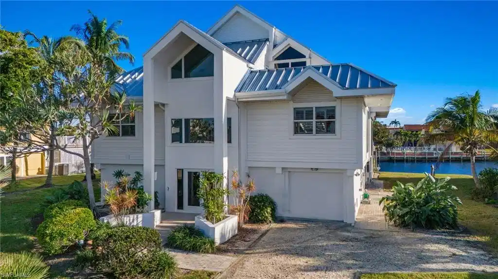 Image 1: View of front facade with a garage, a metal roof, and driveway