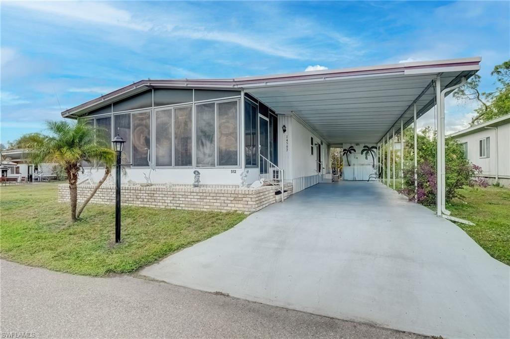 Image 2: View of side of home featuring a carport, a sunroom, a yard, concrete driveway, and a patio area