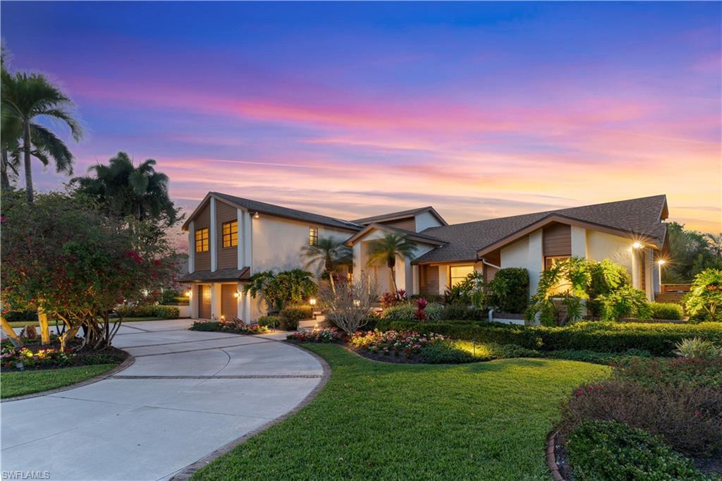 Image 3: View of front of property with a yard, stucco siding, and curved driveway