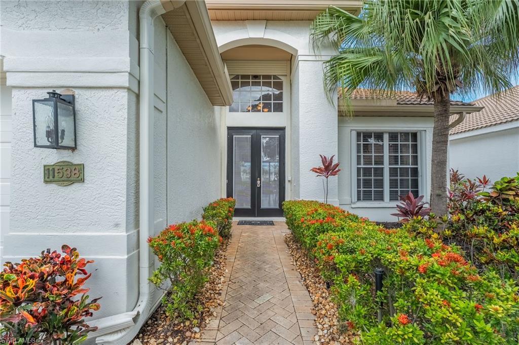Image 2: Stucco exterior featuring a paver walkway bordered by maintained shrubs and landscaping