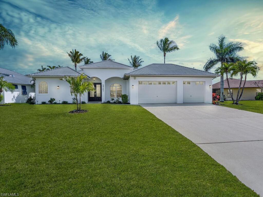 Image 2: View of front of house with an attached garage, a front lawn, driveway, stucco siding, and a tiled roof