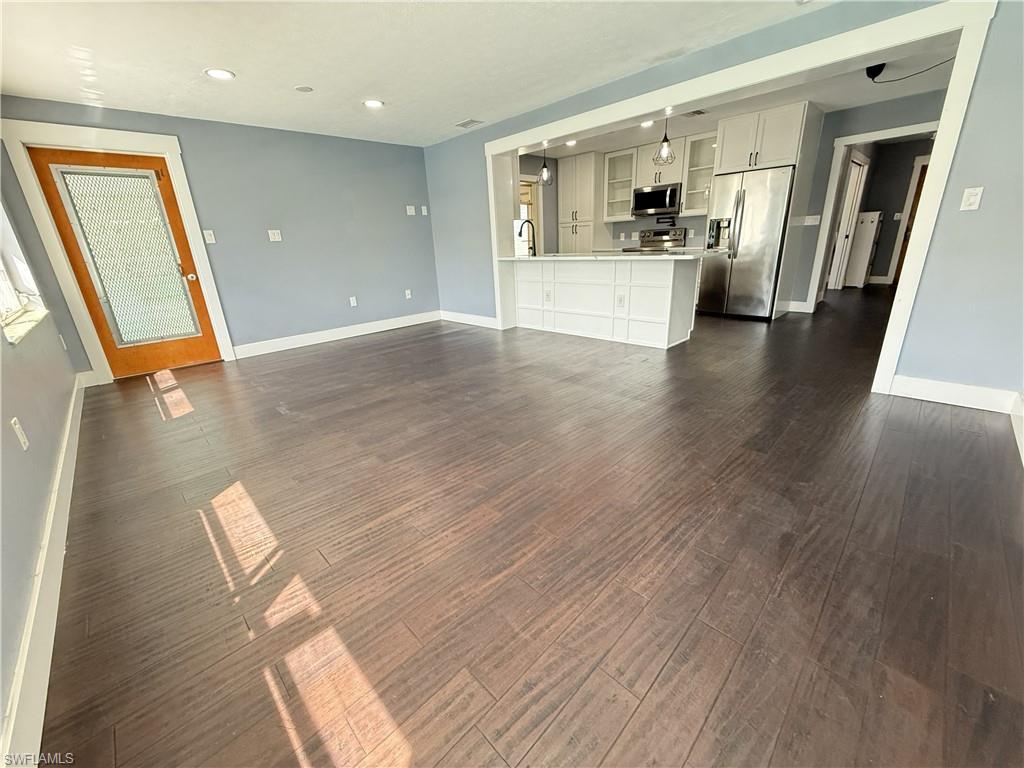 Image 4: Unfurnished living room with dark wood-style flooring and recessed lighting