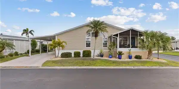 Image 2: Manufactured / mobile home with an attached carport, a sunroom, driveway, and a front yard