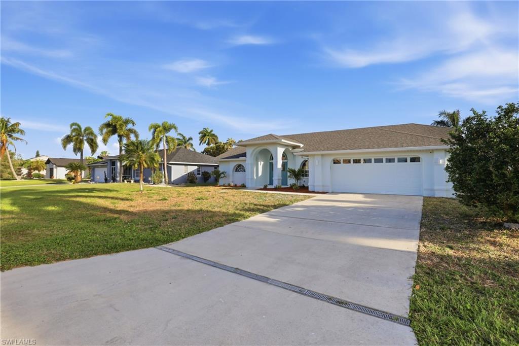 Image 3: Contemporary exterior with an arched entryway, mature palm trees, a concrete driveway, and an attached two-car garage