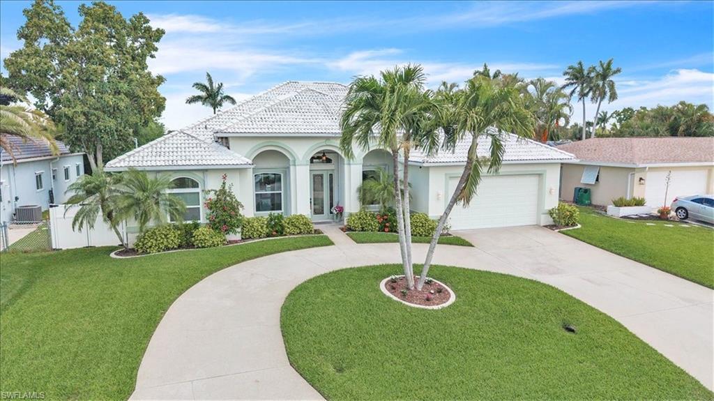 Image 1: Mediterranean / spanish-style house with stucco siding, curved driveway, a front yard, a concrete tiled roof, and a garage