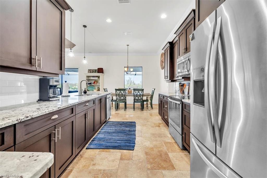 Image 3: Galley kitchen featuring dark wood cabinetry, light-toned granite countertops, and a subway tile backsplash