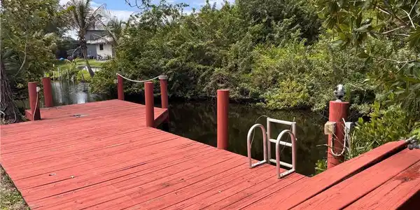 Image 3: The property features a red wooden dock with a rope railing, providing direct access to the canal
