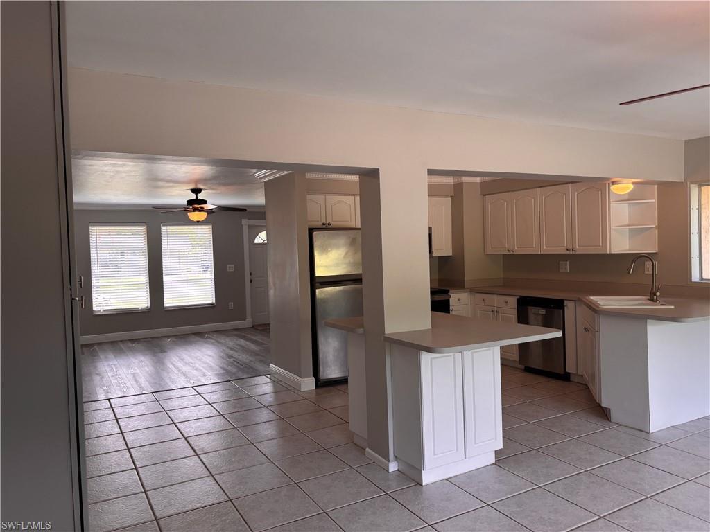Image 4: The property features a kitchen with white cabinetry, a stainless steel refrigerator, and a sink with a gooseneck faucet