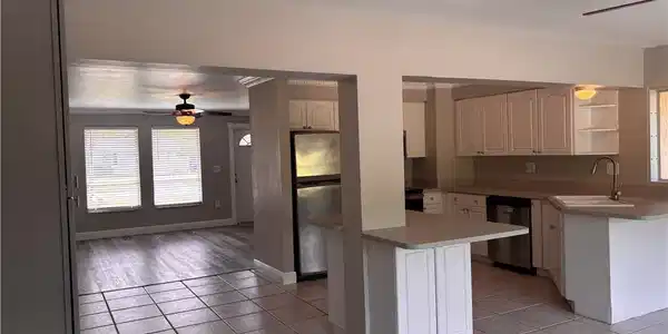 Image 4: The property features a kitchen with white cabinetry, a stainless steel refrigerator, and a sink with a gooseneck faucet