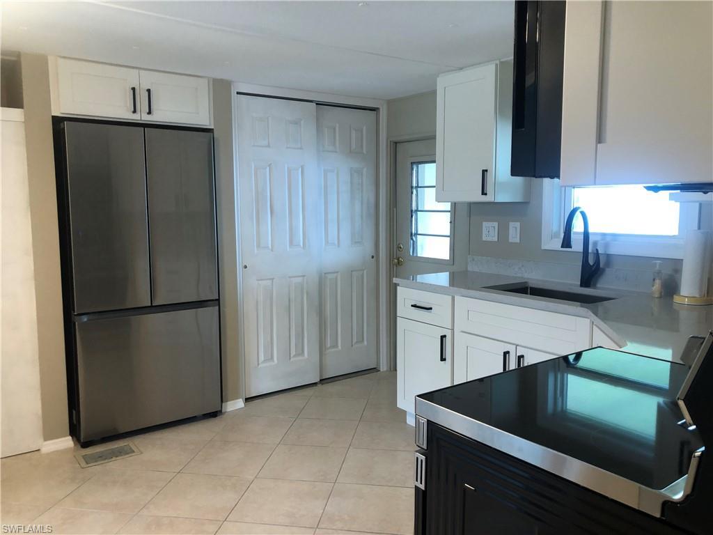Image 3: Kitchen featuring stainless steel appliances refrigerator, sink, and white cabinets