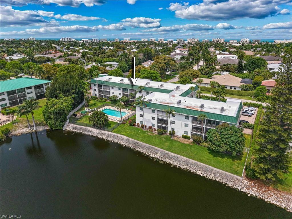 Image 1: Waterfront condominium complex featuring a community pool, mature palm trees, and a manicured lawn