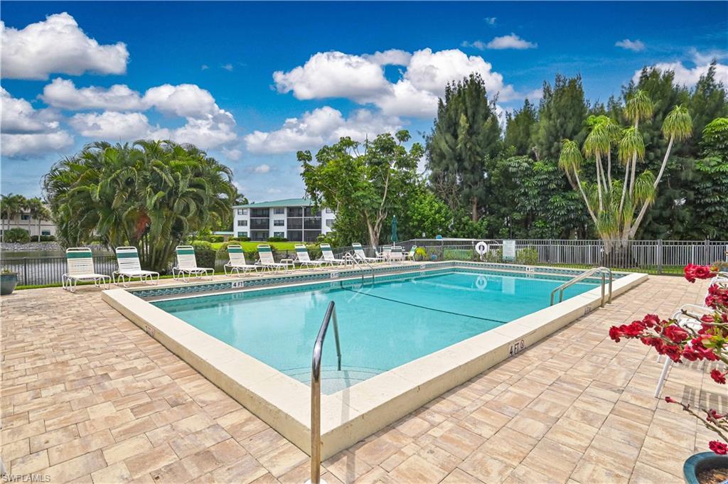 Image 3: Outdoor swimming pool with integrated steps, surrounded by a paver patio and a metal fence