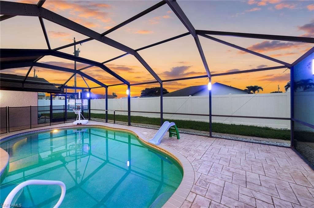 Image 2: Screened-in pool area featuring a freeform swimming pool, decorative stamped concrete patio, and a privacy fence