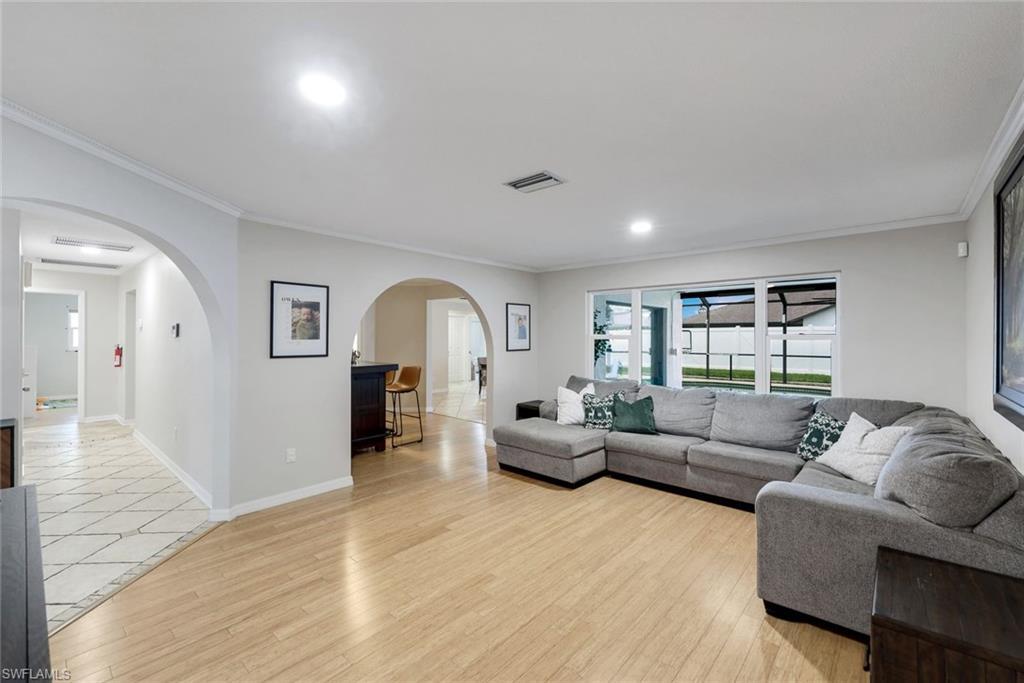 Image 3: Spacious living area featuring wood-finish flooring, recessed lighting, and crown molding