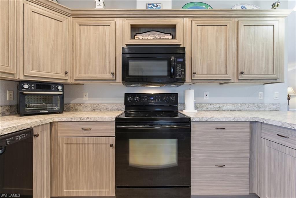Image 2: Kitchen featuring black appliances, light brown cabinets, and light countertops