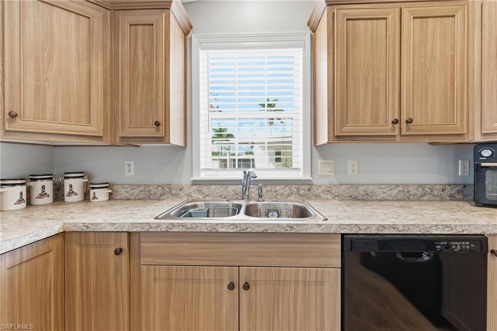 Image 3: Kitchen with black dishwasher, light countertops, and light brown cabinets