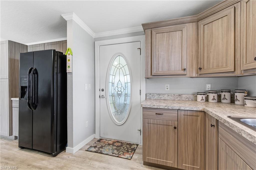 Image 4: Kitchen featuring black refrigerator with ice dispenser, light countertops, light wood-style flooring, and ornamental molding