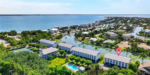Image 2: Waterfront community featuring canal access, multiple residential structures, a tennis court, and an outdoor swimming pool