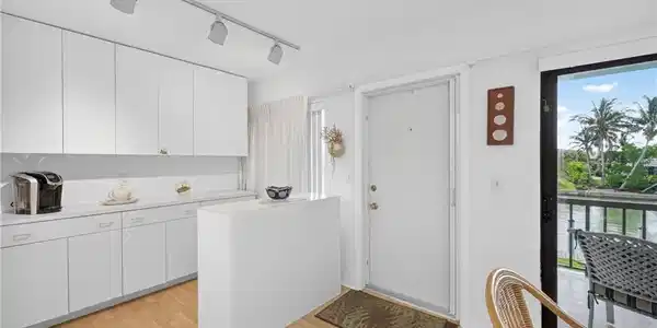 Image 4: Kitchen featuring white cabinetry, track lighting, and wood-finish flooring