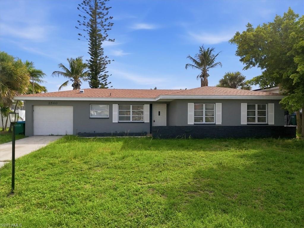 Image 2: Single-story residence featuring a gray exterior, white window shutters, and an attached garage