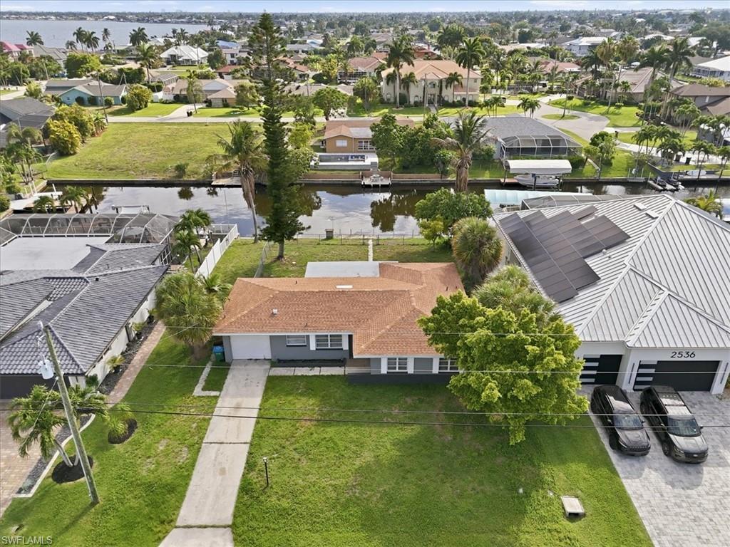 Image 4: Waterfront property featuring a single-story residence with a terracotta-colored roof and an expansive green lawn