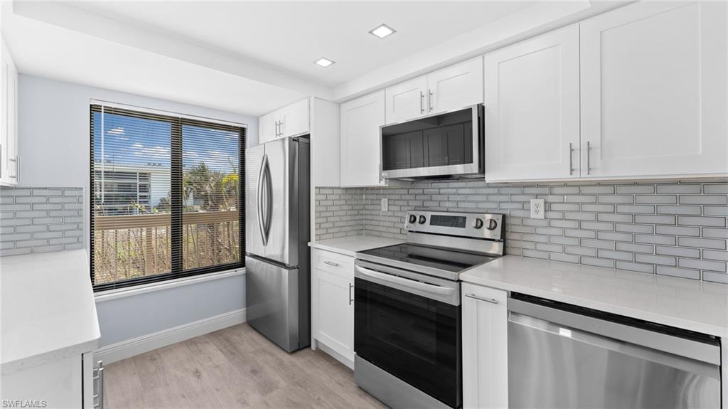 Image 4: Kitchen featuring appliances with stainless steel finishes, light stone counters, white cabinets, and tasteful backsplash